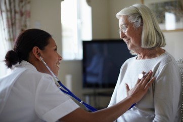 Nurse examining older woman in home